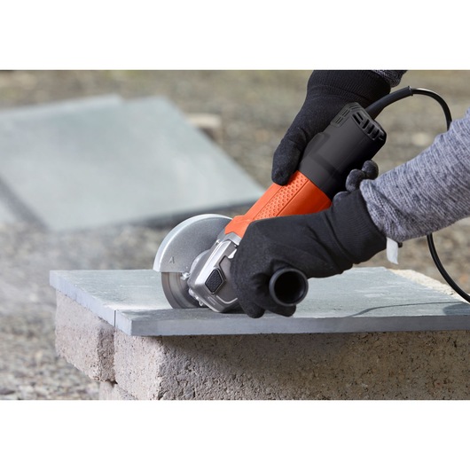 BLACKDECKER BEG110K angle grinder cutting stone, close-up outdoor photography.