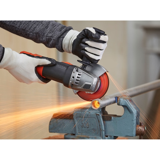 BLACKDECKER BEG120 angle grinder cutting metal pipe, sparks flying, worker wearing gloves.