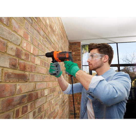 BLACKDECKER BEH550K corded drill used by person in gloves on brick wall, indoor setting.