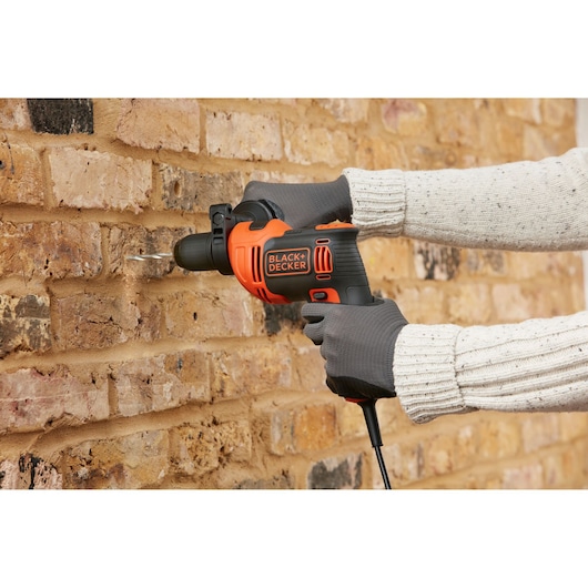 BLACK+DECKER BEH710K corded drill in use on brick wall, orange and black design, photography category.