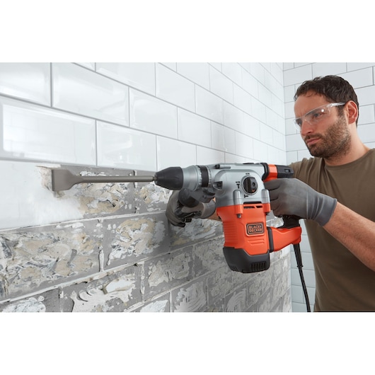 BLACKDECKER BEHS03K rotary hammer used to remove tiles from wall, close-up action, visible gray and orange tool.