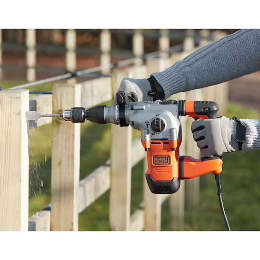 BLACKDECKER BEHS03K corded rotary hammer drill used on wooden fence outdoors.
