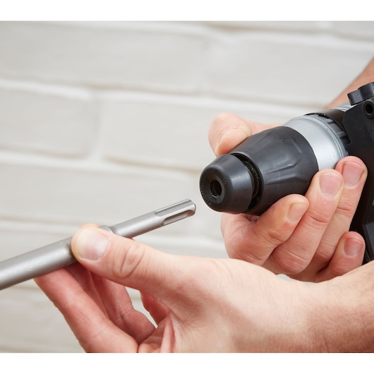 BLACKDECKER BEHS03K rotary hammer drill close-up with hand inserting drill bit, indoor setting, product photography.