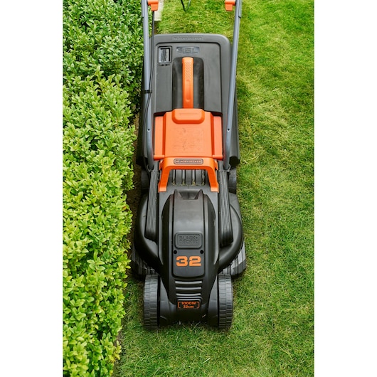 Photo of BLACKDECKER BEMW351 lawn mower on grass, top view showing black and orange body and wheels.