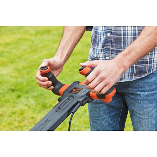 Photo of BLACK+DECKER BEMW461ES lawn mower handle with ergonomic controls outdoors.