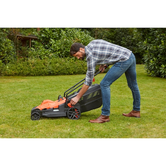 BLACKDECKER lawn mower BEMW461ES with man adjusting height in garden setting.