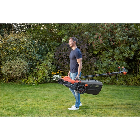 BLACKDECKER BEMW471ES lawn mower with handle, carried outdoors by a person on grass.