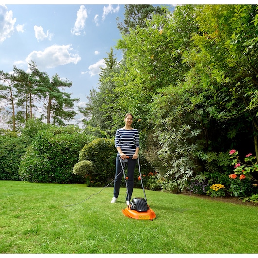 BLACKDECKER BEMWH551 lawn mower with handle, orange and black, used outdoors on green grass.