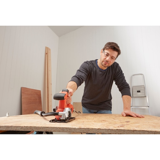 BLACKDECKER BES510K compact circular saw used on wood panel in workshop setting.
