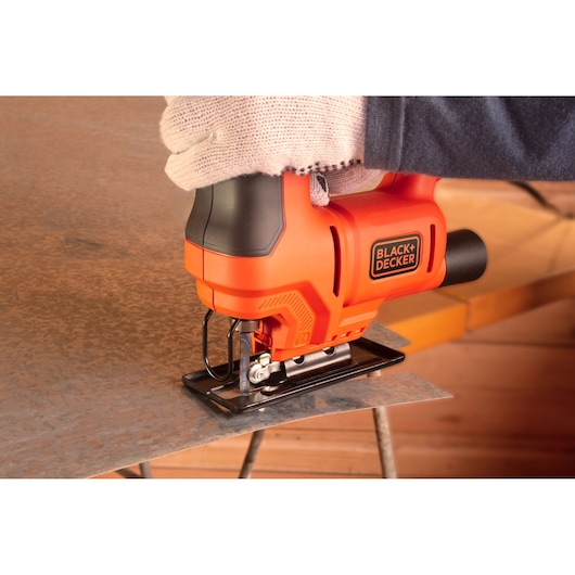 BLACK+DECKER BES603 jigsaw cutting metal sheet, side view, orange and black design.