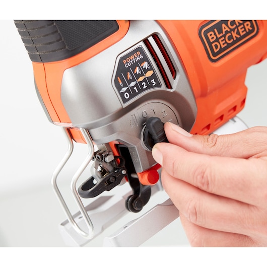 Close-up photo of BLACK+DECKER BES610K jigsaw control being adjusted by hand, orange and black body.