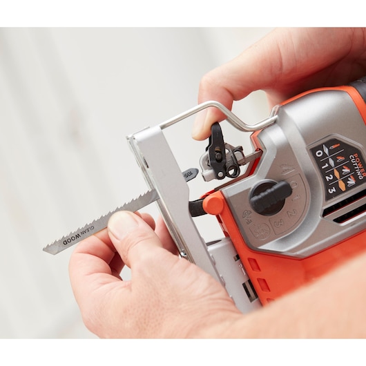 Photo of BLACKDECKER BES610 jigsaw with a close-up of a hand installing a saw blade, showing adjustment controls.