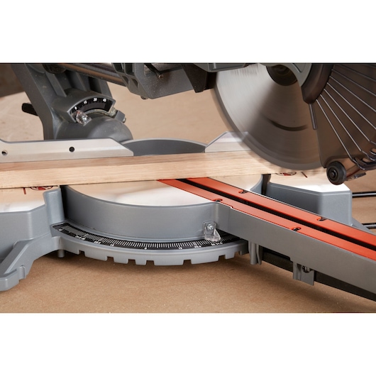 BLACKDECKER BES700 mitre saw cutting wood, close-up side angle on work surface.