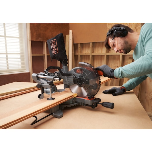BLACKDECKER BES701 miter saw cutting wood in workshop, side angle, person operating.
