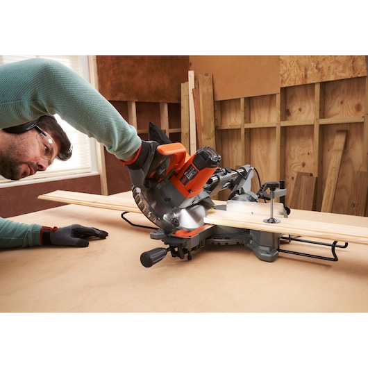 BLACKDECKER BES701 miter saw cutting wood planks on a workbench in workshop setting.