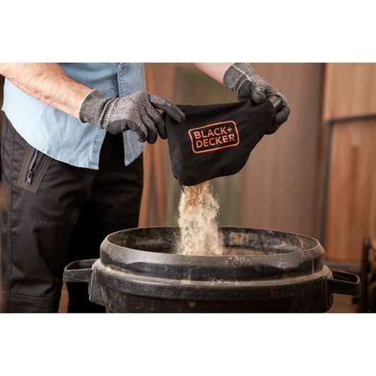 BLACKDECKER BES710 dust bag emptied into a bin, close-up of product and gloves.