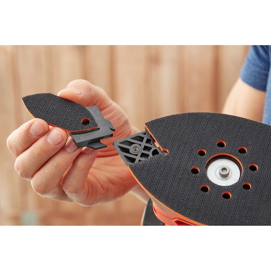 Close-up photo of BLACKDECKER BEW200K sander accessory being attached to sanding pad.