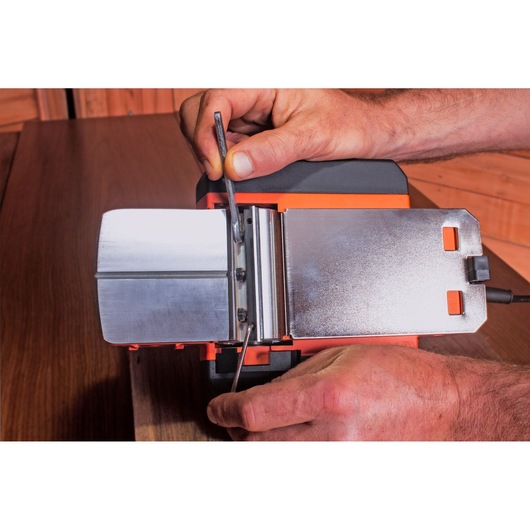 BLACKDECKER BEW712 power tool with metal base, shown in close-up during adjustment on wooden surface.