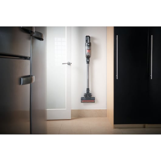 BLACKDECKER BHFEA18D1 cordless stick vacuum mounted on a kitchen wall, shown upright for storage.