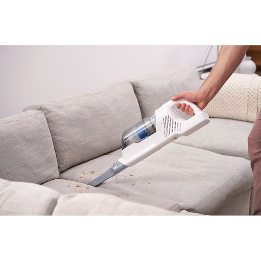 BLACKDECKER BHFEA420J cordless vacuum cleaning crumbs from a grey sofa, handheld view.