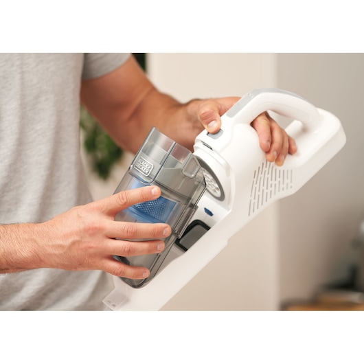 Photo of BLACKDECKER BHFEA420J handheld vacuum with person removing dust container.