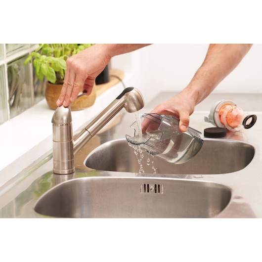 BLACKDECKER BHFEA515J vacuum dust container rinsed under kitchen sink faucet, photo of cleaning process.