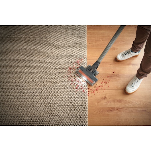 BLACKDECKER BHFEA520J vacuum cleaning carpet and wood floor with LED light, picking up red debris.