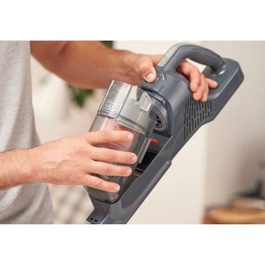 Photo of BLACKDECKER BHFEA520J cordless vacuum cleaner with a person removing the dust container.