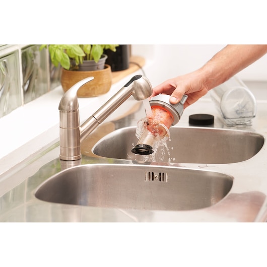 BLACKDECKER BHFEA520J vacuum filter being rinsed under kitchen faucet over stainless steel sink.