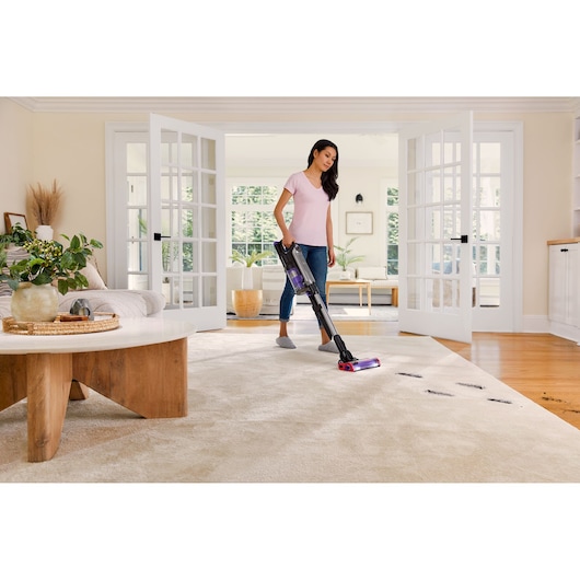 BLACKDECKER BHFEA640WP cordless stick vacuum in use cleaning a light carpet in a modern living room.