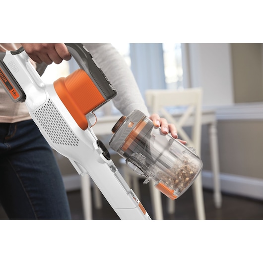 BLACKDECKER BHFEV1825C cordless stick vacuum being emptied, shown in close-up indoor setting.