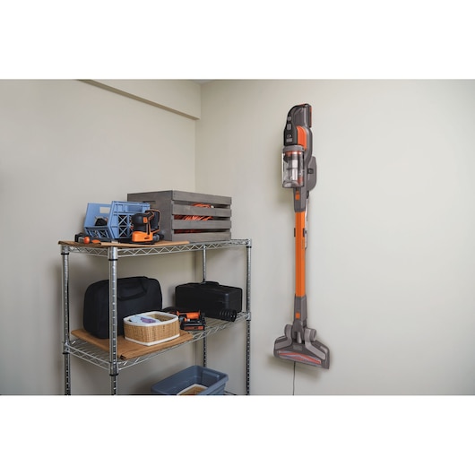 BLACKDECKER BHFEV182B cordless stick vacuum mounted on wall next to shelving, indoor setting.