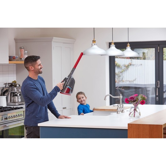 BLACKDECKER BHHV315J handheld vacuum cleaner used to clean pendant lights in a modern kitchen.