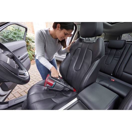 BLACKDECKER BHHV315J handheld vacuum cleaning black car seat in interior setting.