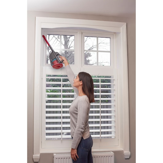 BLACKDECKER BHHV315J handheld vacuum cleaning window frame, indoor setting, side view.