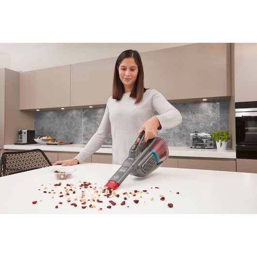 BLACKDECKER BHHV315J handheld vacuum cleaning crumbs on a white kitchen counter.