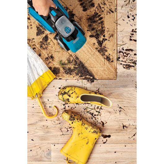 BLACKDECKER BHSB320JP handheld vacuum cleaning muddy entry mat, yellow boots and umbrella on wood floor.