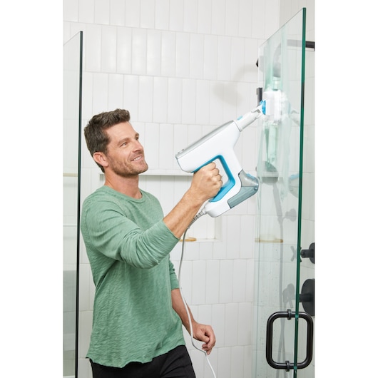 BLACKDECKER BHSM15FX08 steam cleaner used to clean a glass shower door in a bathroom.