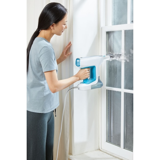 BLACKDECKER BHSM15FX08 handheld steam cleaner in use on window glass.