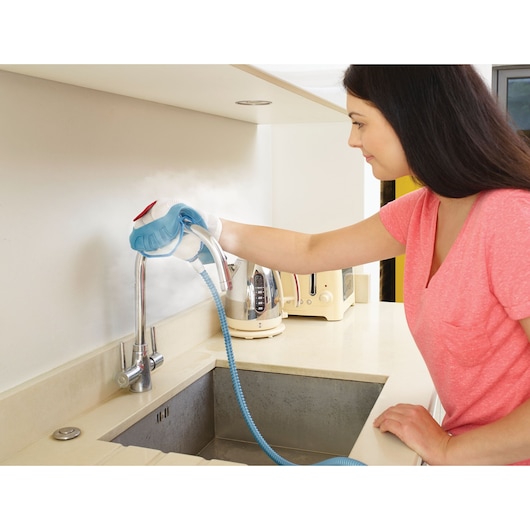 BLACKDECKER BHSM1615DAM handheld steam cleaner used on kitchen faucet and counter.