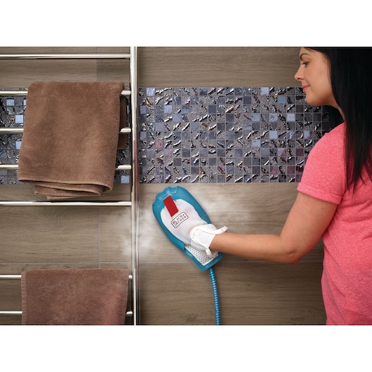 Photo of BLACKDECKER BHSM1615DAM handheld steam cleaner in use on bathroom wall tiles.