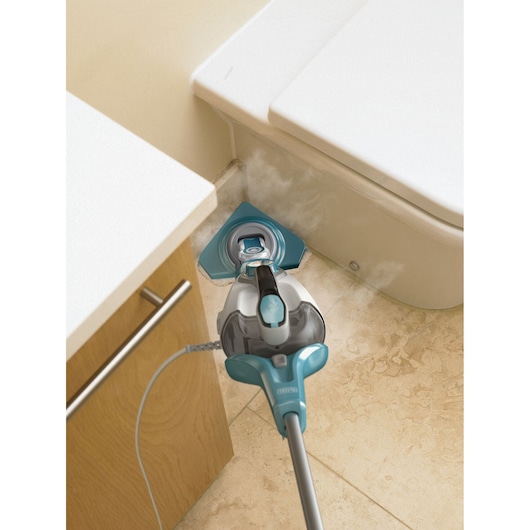 BLACKDECKER BHSM1615DAM steam mop cleaning tight bathroom corner between cabinet and toilet, steam visible.