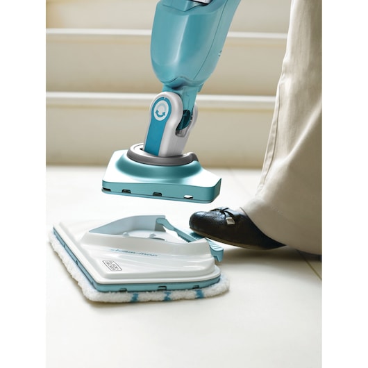 BLACKDECKER BHSM1615DAM steam mop pad being attached with foot, showing blue and white cleaning head close-up.