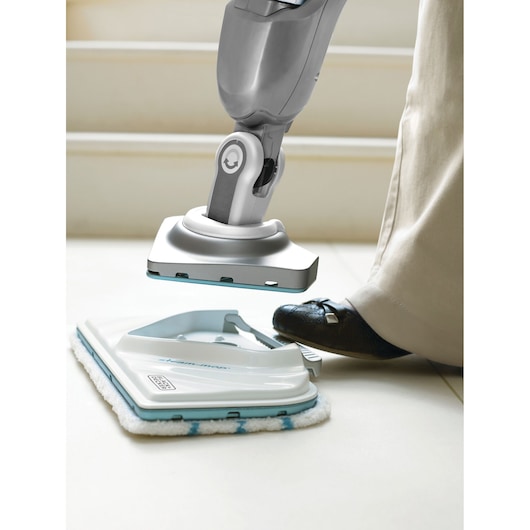 BLACK+DECKER BHSM1615DSG steam mop close-up with person pressing cleaning pad on floor.