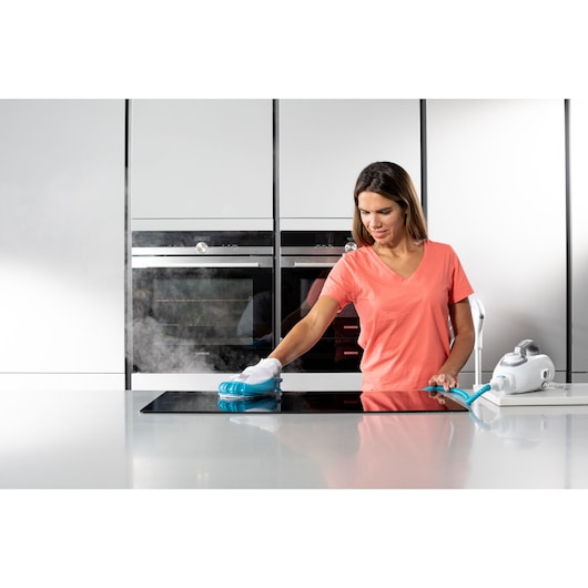 Photo of person cleaning kitchen counter with BLACK+DECKER steam cleaner BHSM1615DSG, white and blue device visible.
