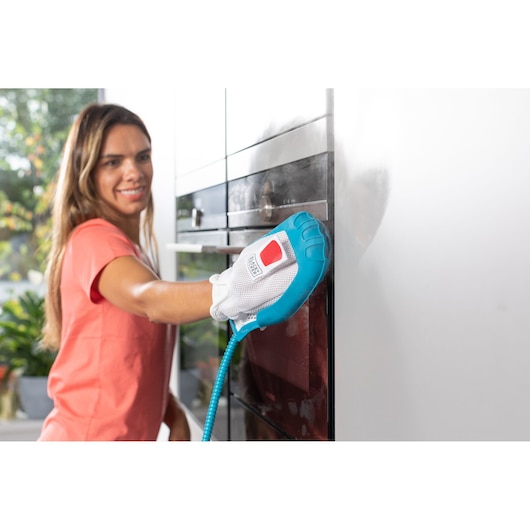 BLACKDECKER BHSM1615DSG steam cleaning glove in blue and white used on kitchen cabinet.