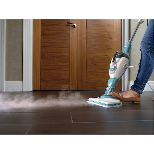 BLACKDECKER BHSM168DSM steam mop in use on dark tile floor, person pressing pedal, steam visible.