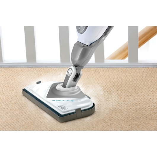 BLACKDECKER BHSM168D steam mop cleaning beige carpet, close-up angle.