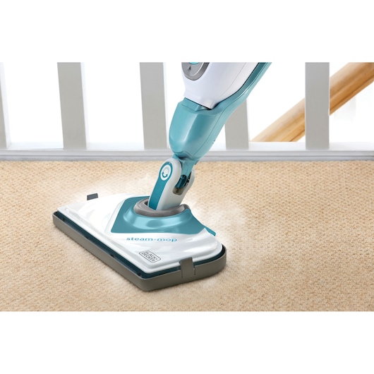 BLACKDECKER BHSM168U steam mop cleaning beige carpet, photography close-up of mop head in use.