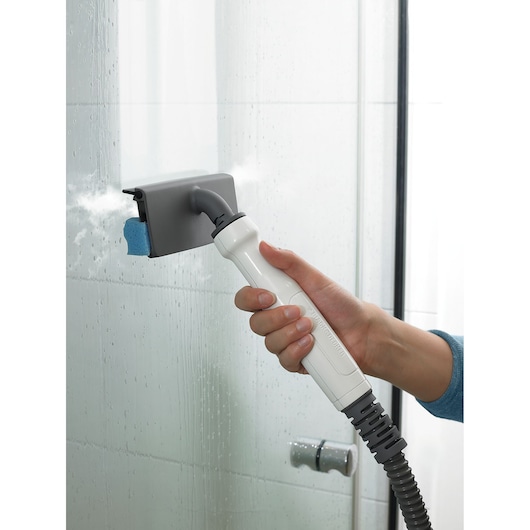 BLACKDECKER BHSM169DSM steam cleaner being used to clean a glass shower door, close-up view.